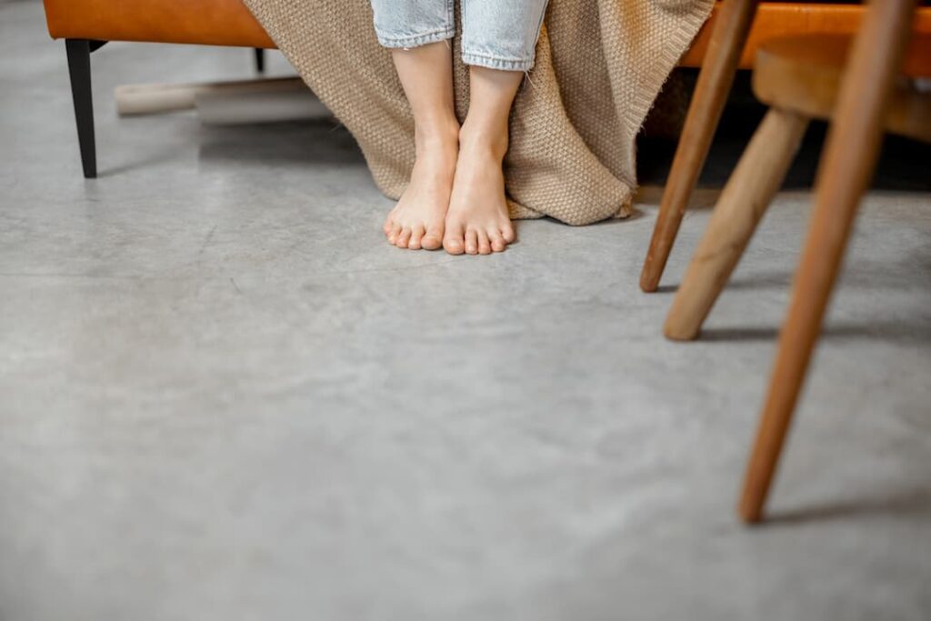Femme assise pieds nus sur un sol en PVC ou vinyle, comparatif des revêtements résistants