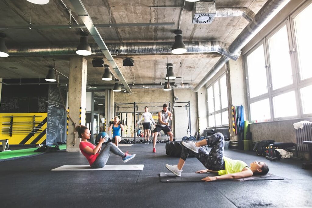 Des personnes faisant des exercices dans une salle de sport équipée d'un sol en dalle amortissantes en caoutchouc.
