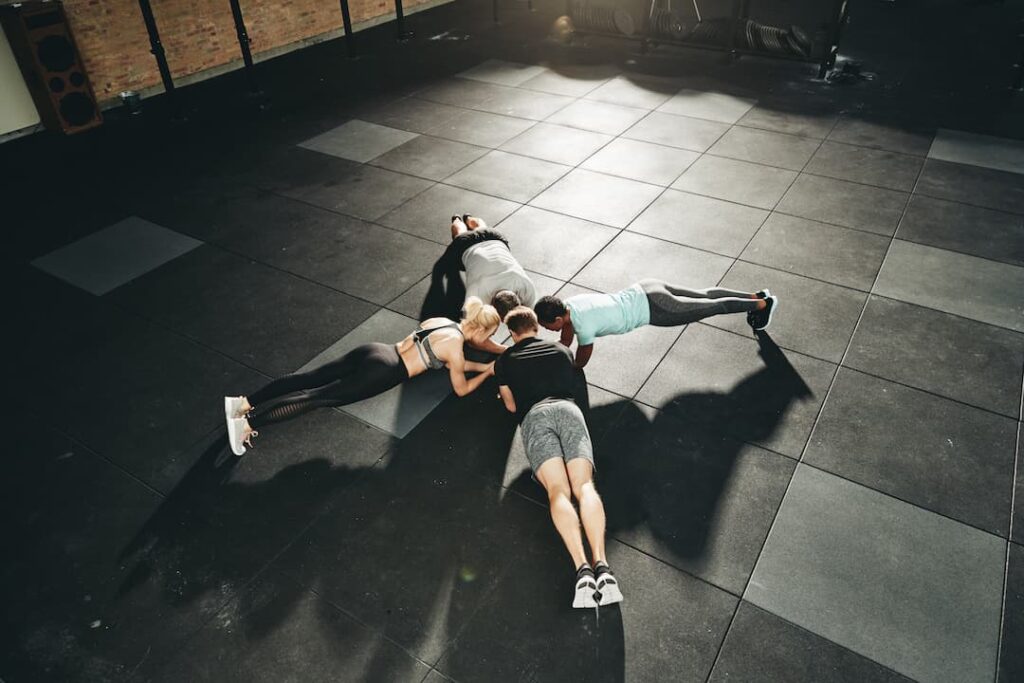 Des personnes faisant du gainage sur des dalles de sport absorbantes dans une salle de sport moderne