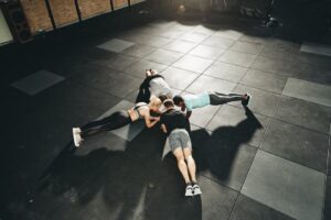 Des personnes faisant du gainage sur des dalles de sport absorbantes dans une salle de sport moderne