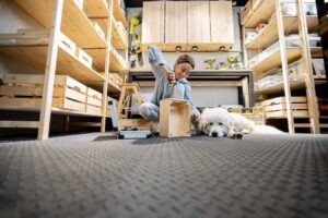 Femme en train de bricoler dans un garage équipé de dalles en PVC avec un chien allongé à ses côtés