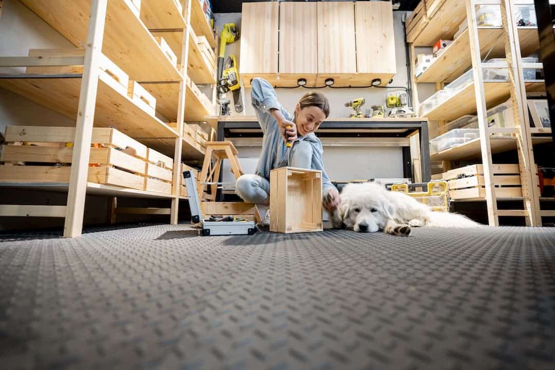 Femme en train de bricoler dans un garage équipé de dalles en PVC avec un chien allongé à ses côtés